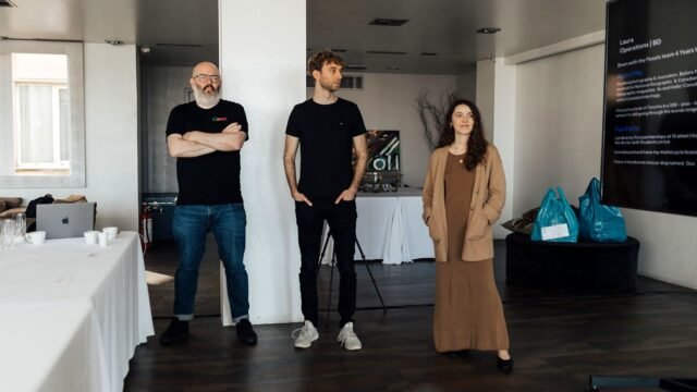 Three people presenting media plans to colleagues in an office meeting room