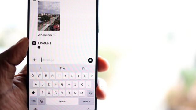 A hand holds a smartphone with a ChatGPT conversation open on the screen.