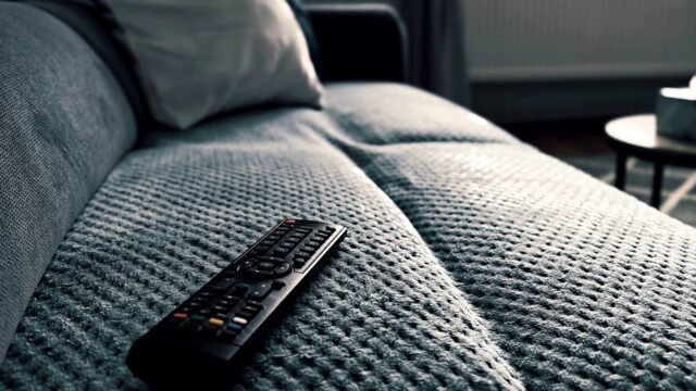 Close-up of a television remote control lying on a sofa