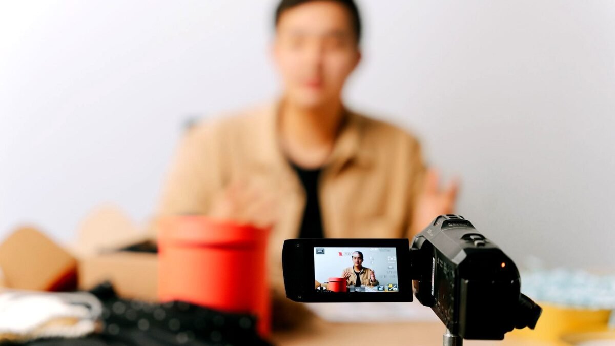 A creator sits in front of a camera and a light, recording a video at home