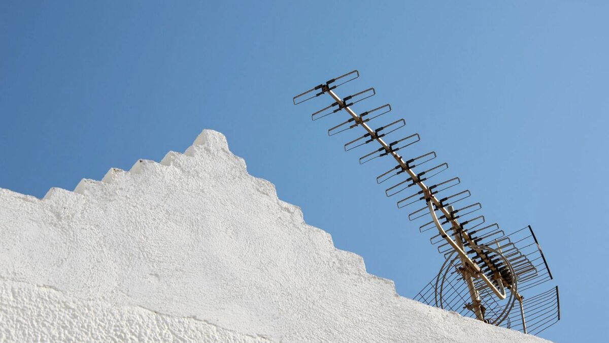 A television aerial mounted on a house roof against a clear sky.