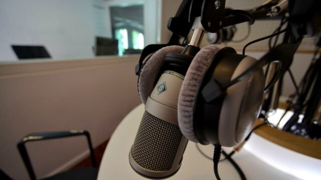 Close-up of a studio microphone with headphones in a recording setting, emphasizing audio quality.