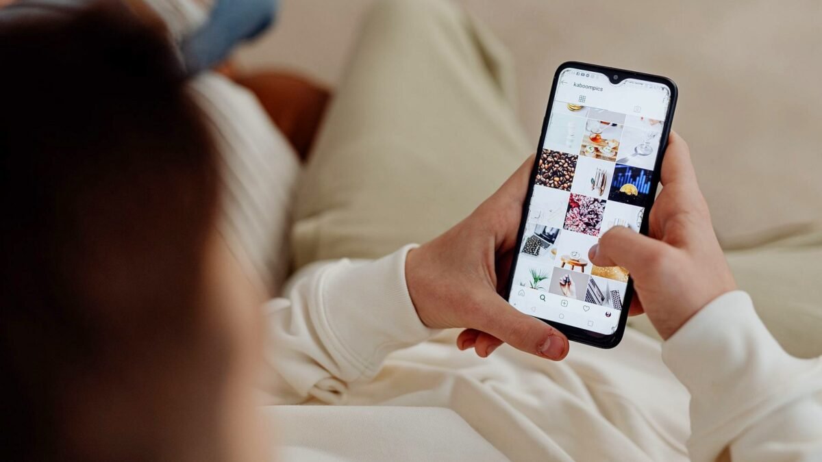 Hand holding a smartphone with the Instagram feed open indoors
