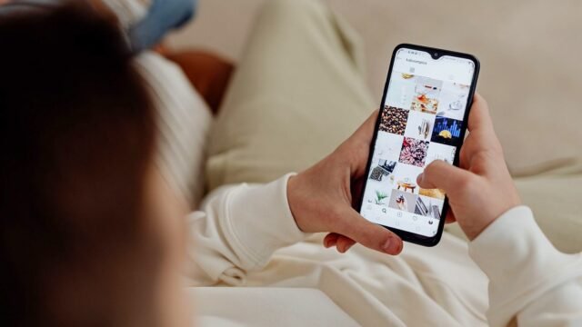 Hand holding a smartphone with the Instagram feed open indoors