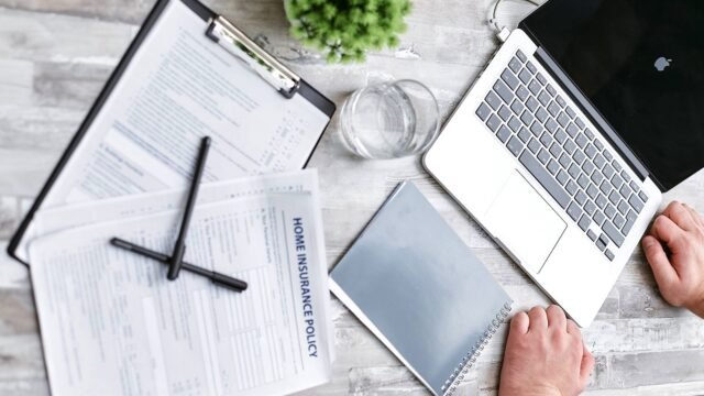 Insurance forms and a laptop on a desk, seen from above