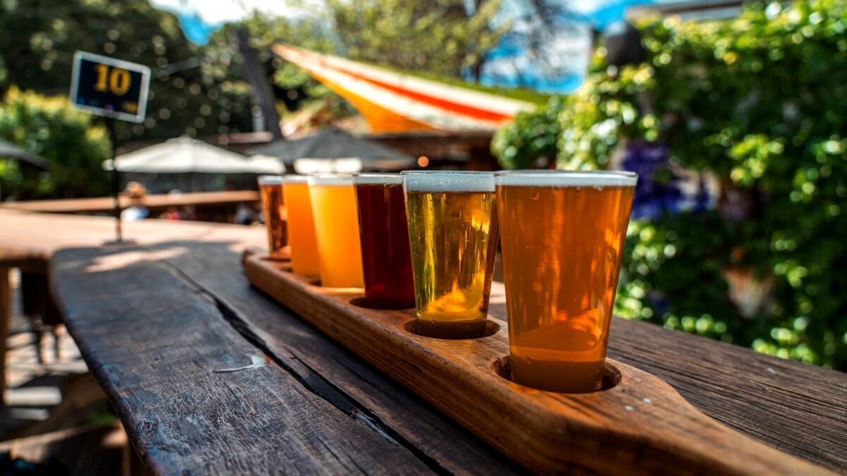 Beer flight of several glasses on a rustic wooden table outdoors
