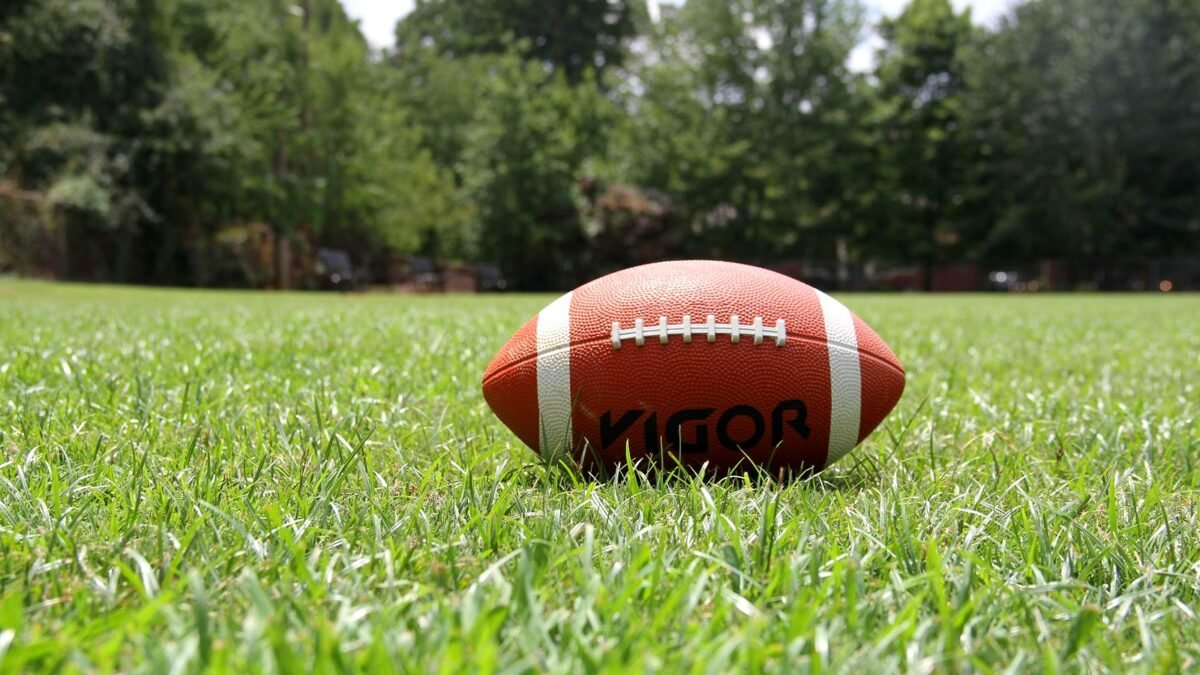 American football lying on the grass of a playing field