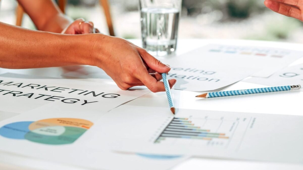 Hands pointing at printed marketing charts on a table during an office meeting