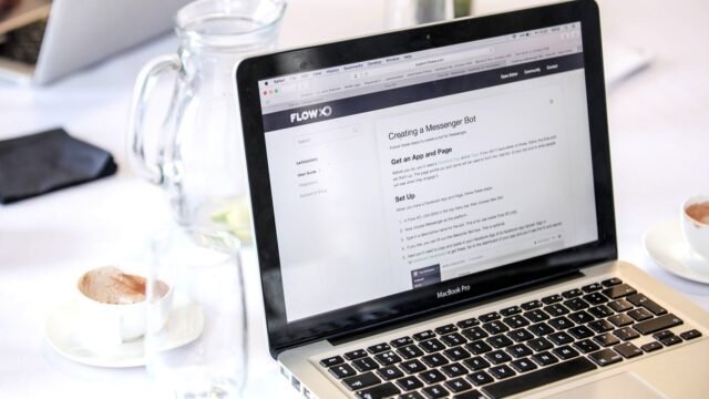 Close-up of an open laptop showing a web page, with a coffee cup beside it on a desk