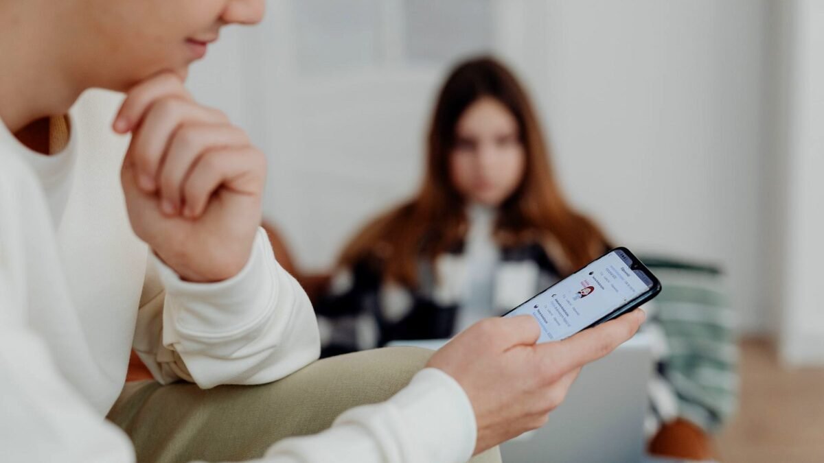 Teens using smartphones indoors with a blurred background, suggesting social media engagement.