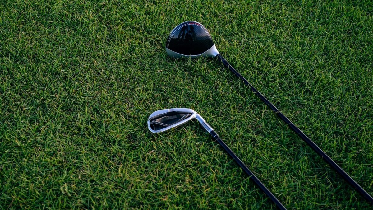 A close-up view of two golf clubs resting on neatly manicured grass, perfect for golf enthusiasts.