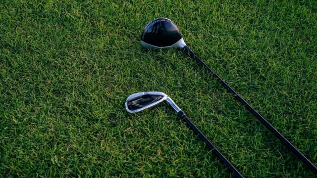 A close-up view of two golf clubs resting on neatly manicured grass, perfect for golf enthusiasts.