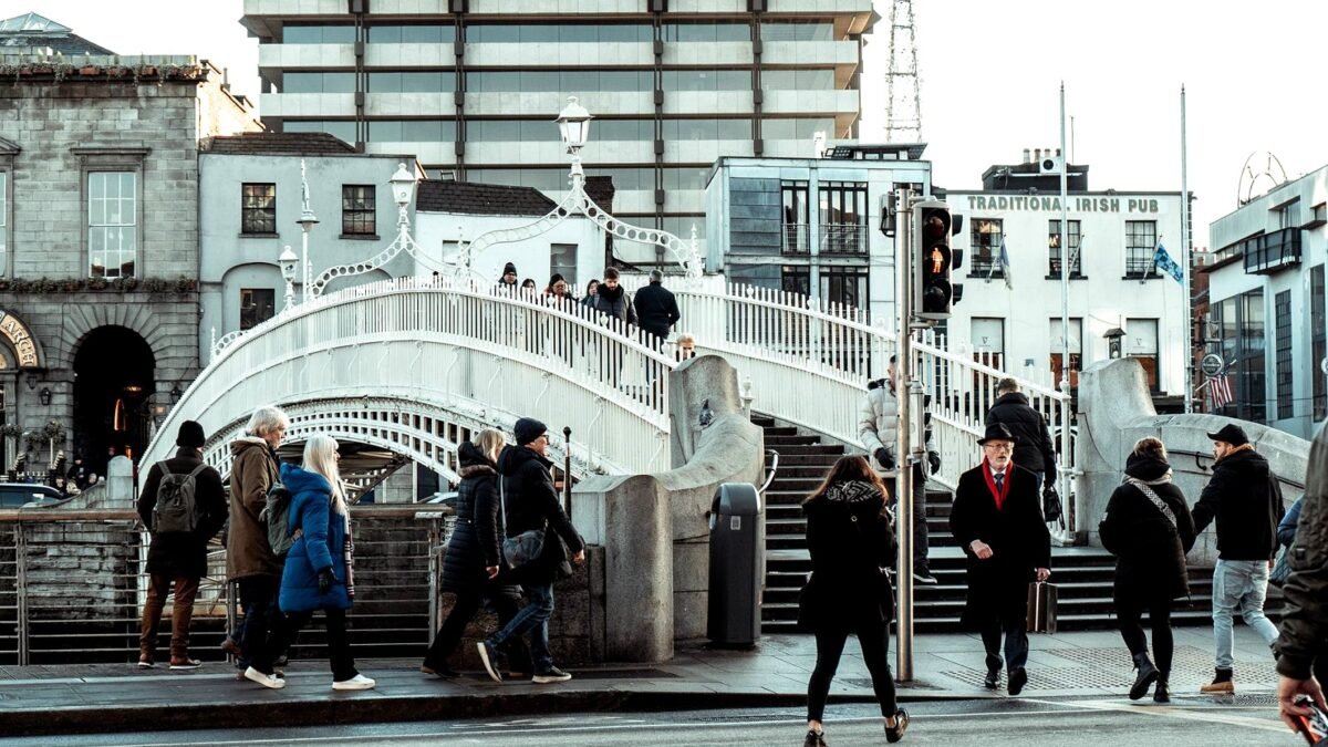 People walking across the Ha’penny Bridge over the river in central Dublin