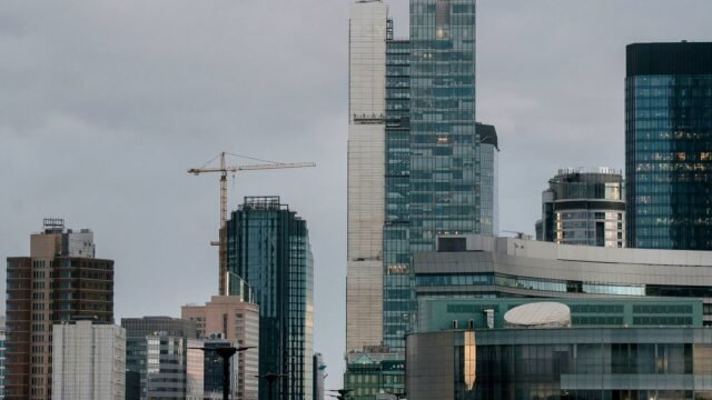 A view of Warsaw skyline featuring contemporary skyscrapers and construction cranes at daytime.