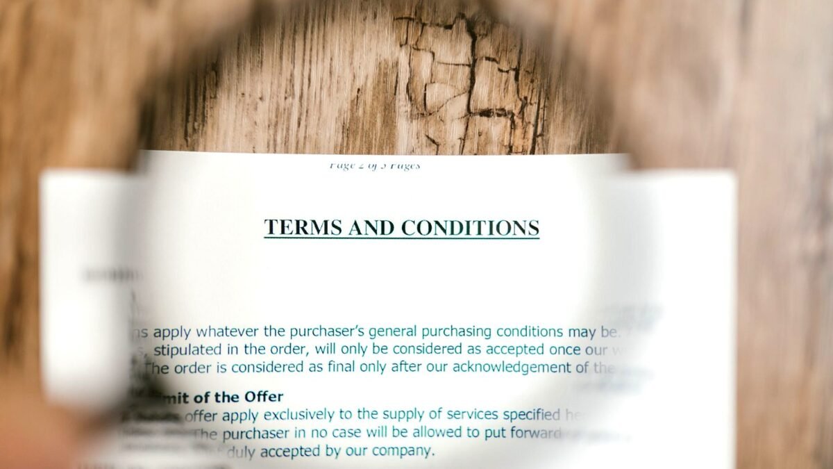 Magnifying glass held over the small print of a terms and conditions document.