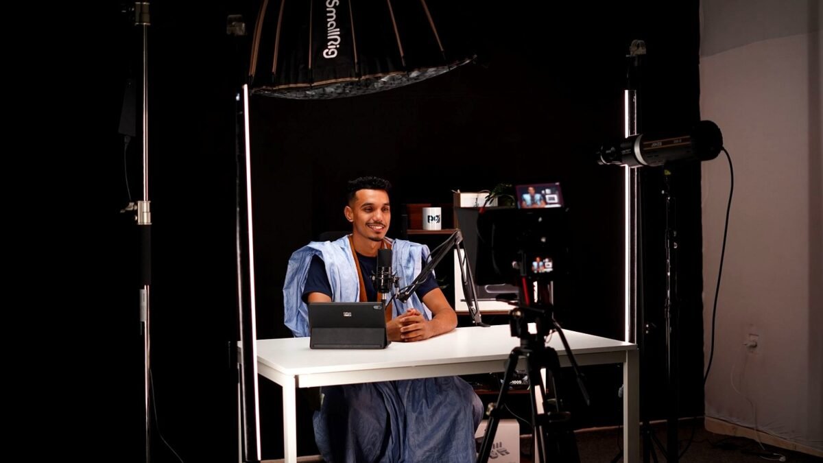 Young man recording a video in a bright studio with camera and lighting equipment