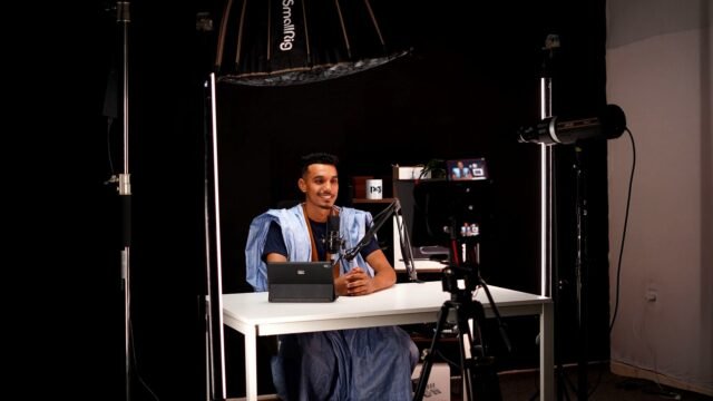 Young man recording a video in a bright studio with camera and lighting equipment