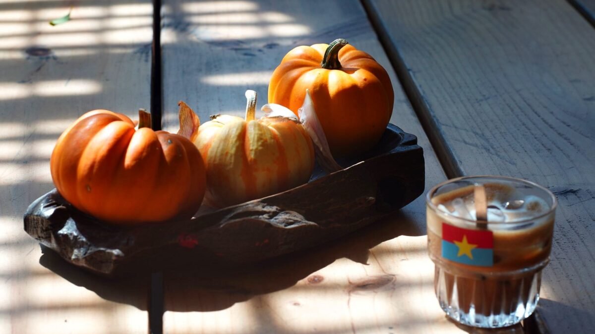 Iced coffee and pumpkins on a sunlit wooden table in autumn