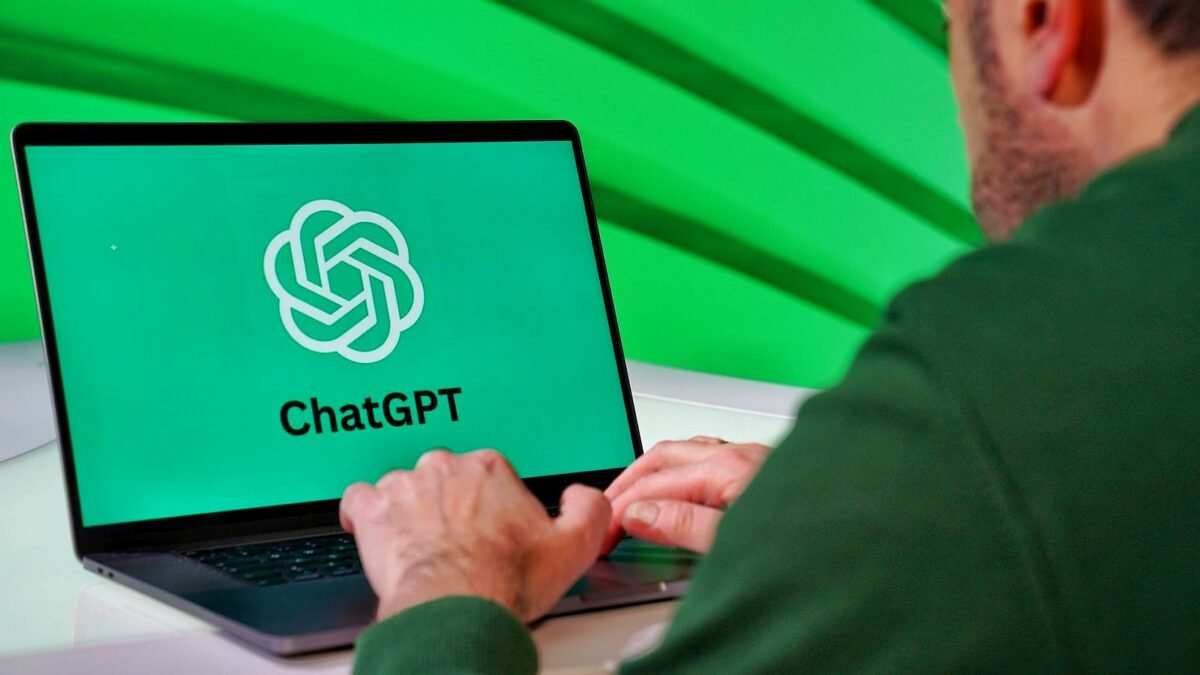 Person typing on a laptop showing the ChatGPT logo on a green screen