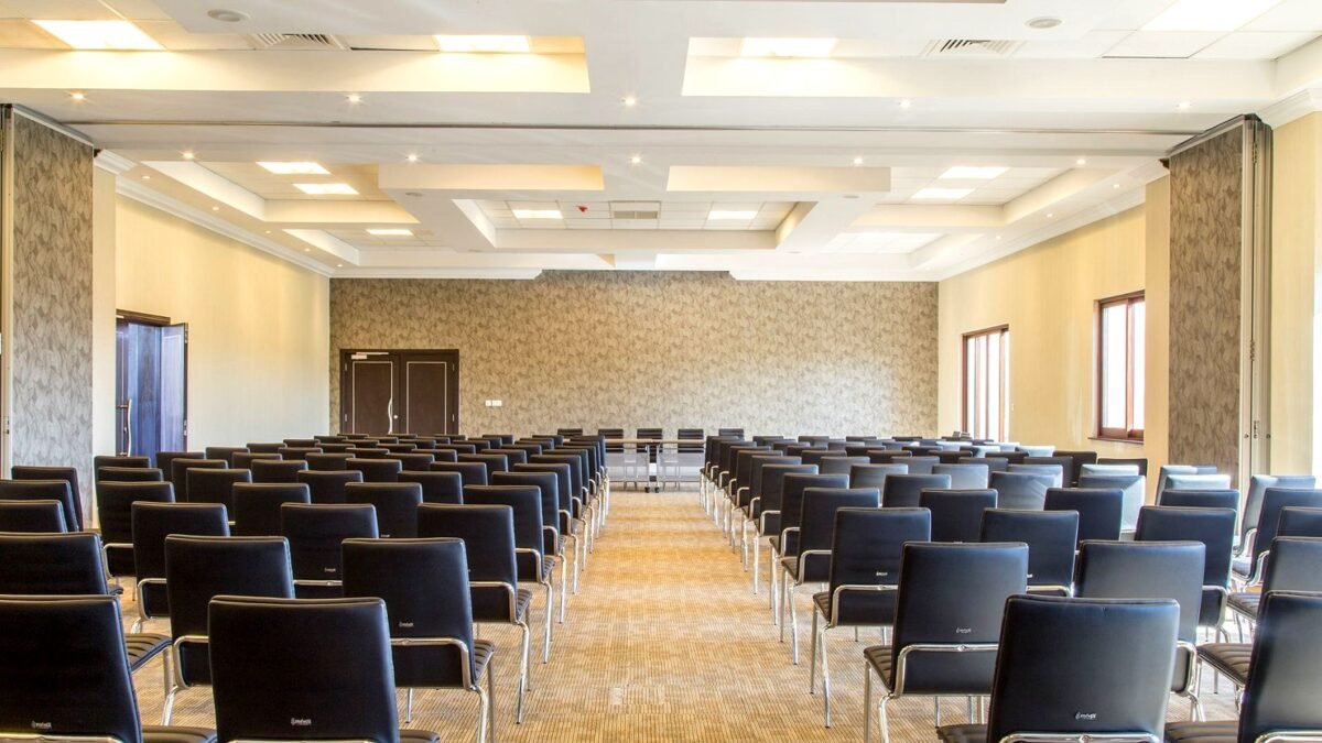 Spacious empty conference room with modern design and neatly arranged black chairs.