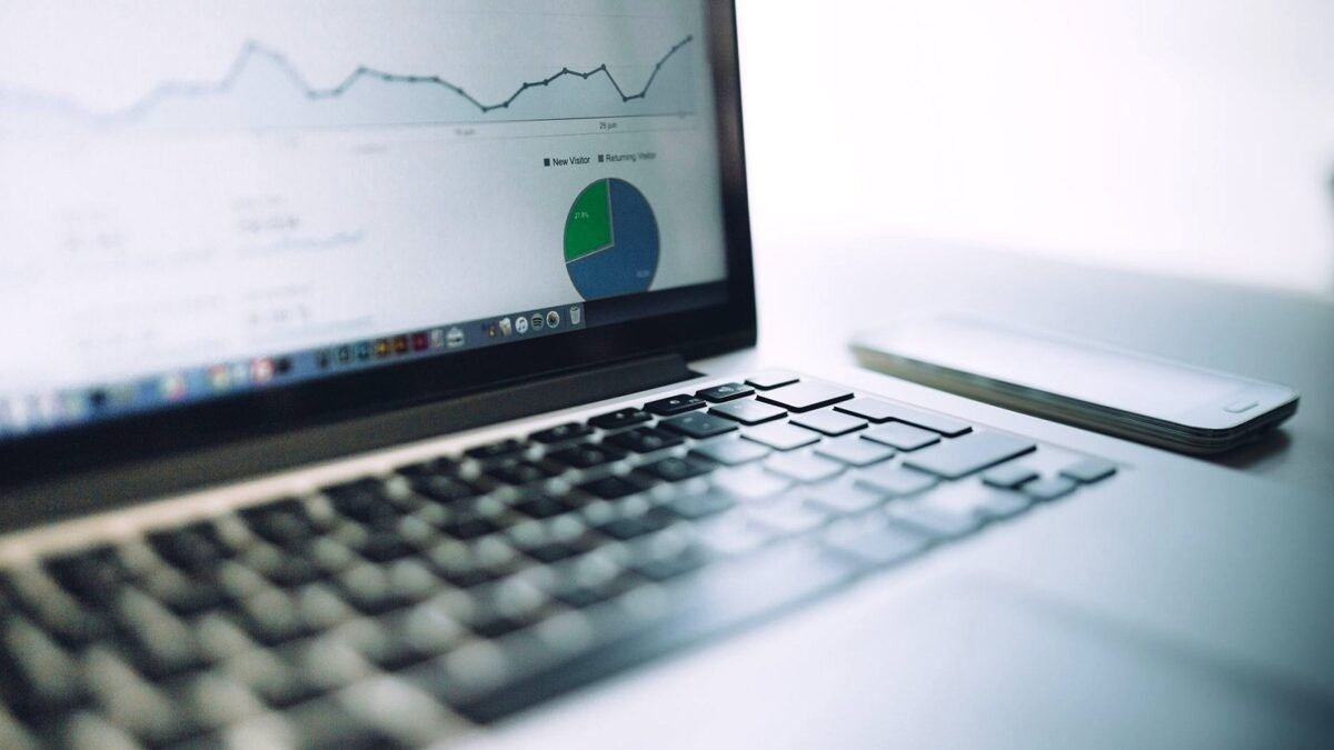 Laptop on a desk showing a reporting dashboard with charts and tables