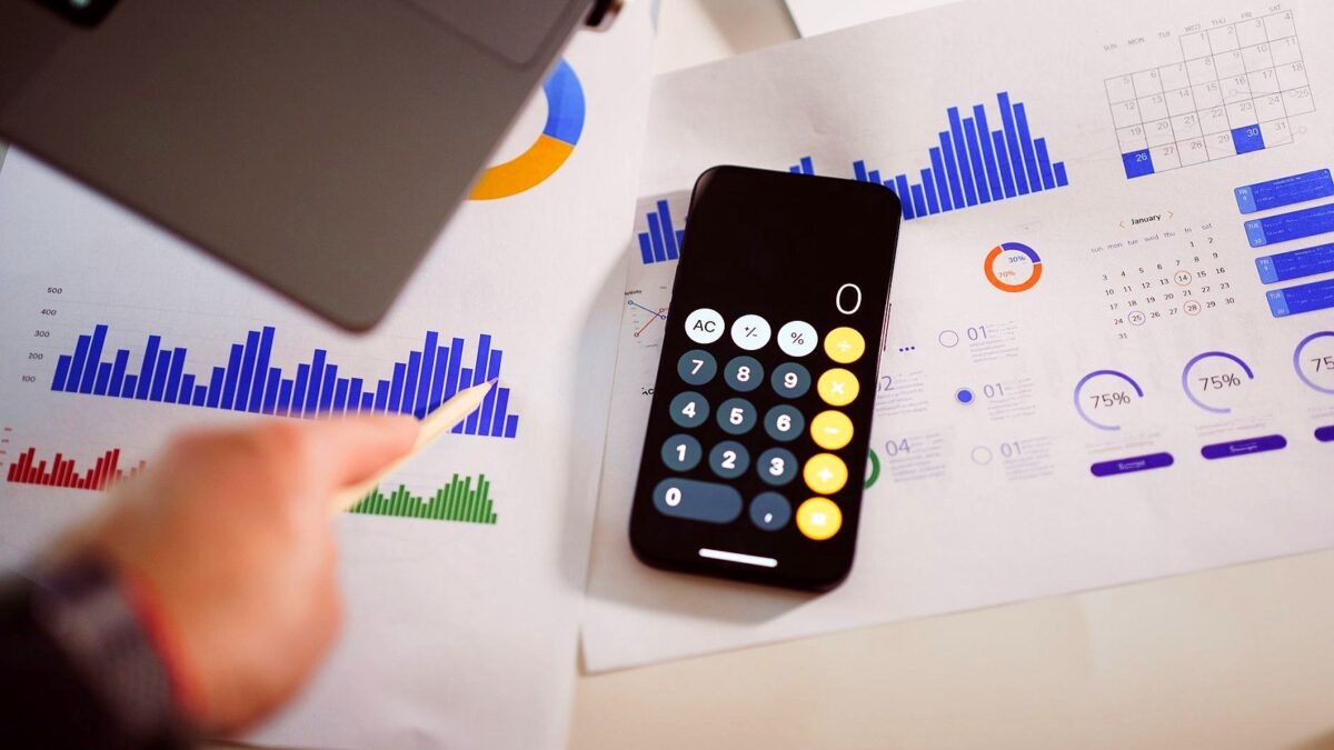 Calculator, printed charts and a pen on a desk during a budget check