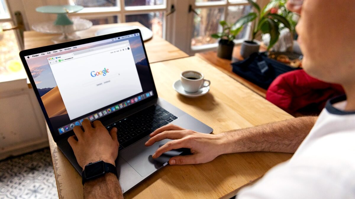 Two people working on laptops with the Google search page open at a café table