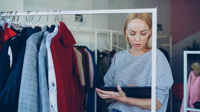 Shop worker checks product stock on a tablet between shelves