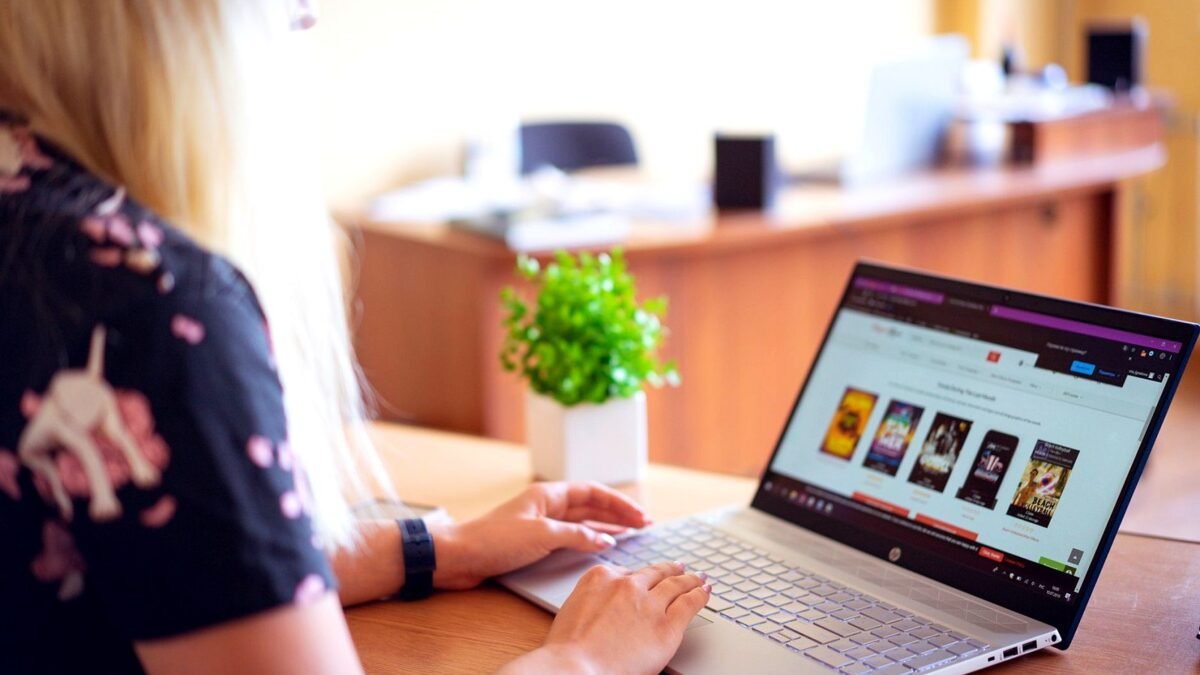 Woman at a laptop browsing an online shop, her hands resting on the keyboard.