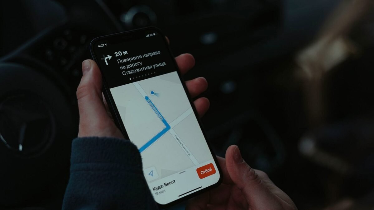 Close-up of a smartphone showing a navigation map held in one hand