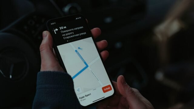 Close-up of a smartphone showing a navigation map held in one hand