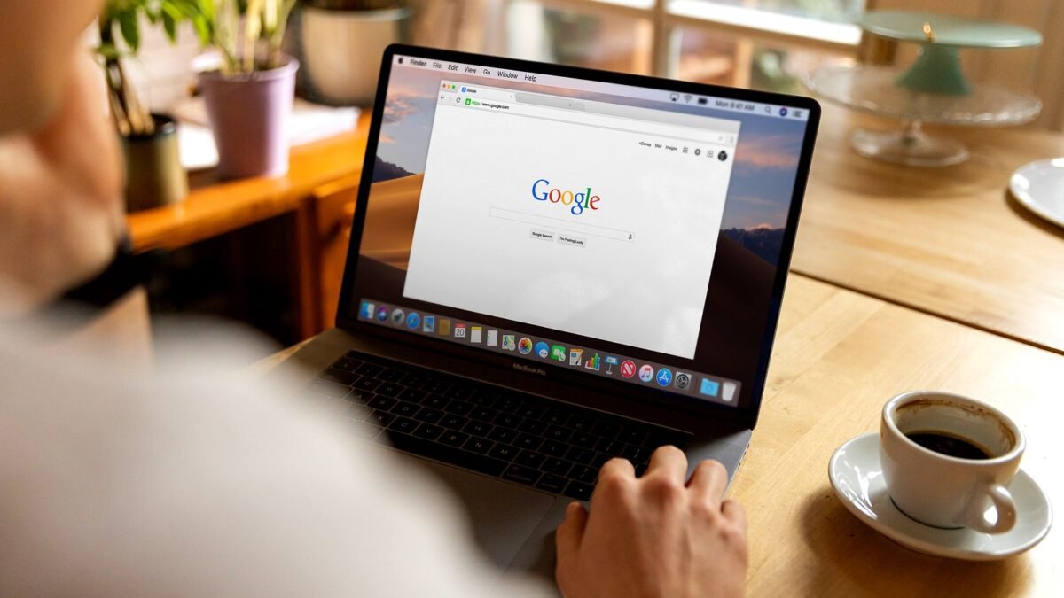 Person browsing Google search on a laptop at a bright wooden desk