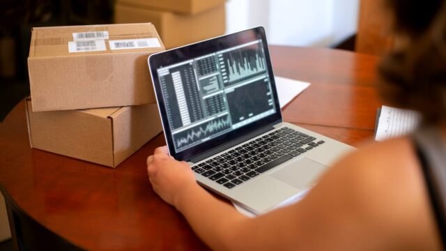 Online shop owner checking orders on a laptop at a work desk