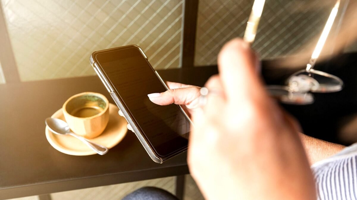 A phone screen and a cup of coffee on a table in an office