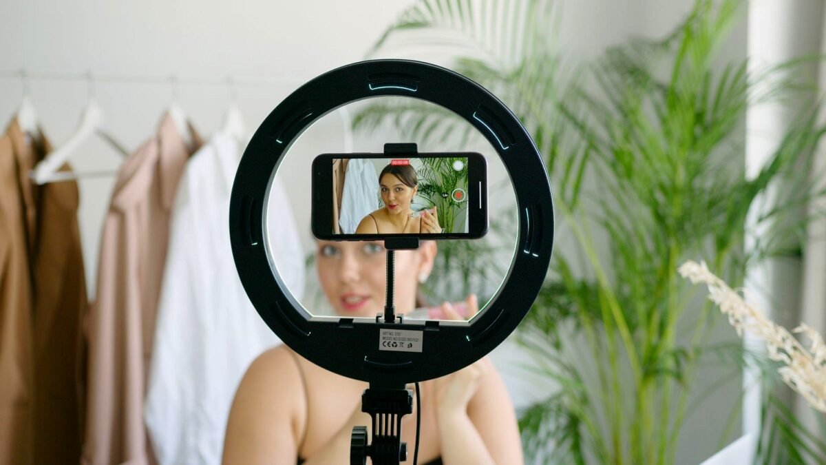 A woman sets up a smartphone and ring light to record a video