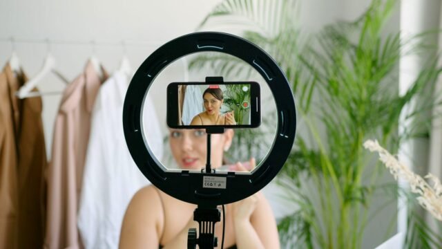 A woman sets up a smartphone and ring light to record a video