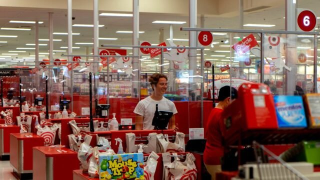 A busy checkout area in a large retail store with shoppers queuing