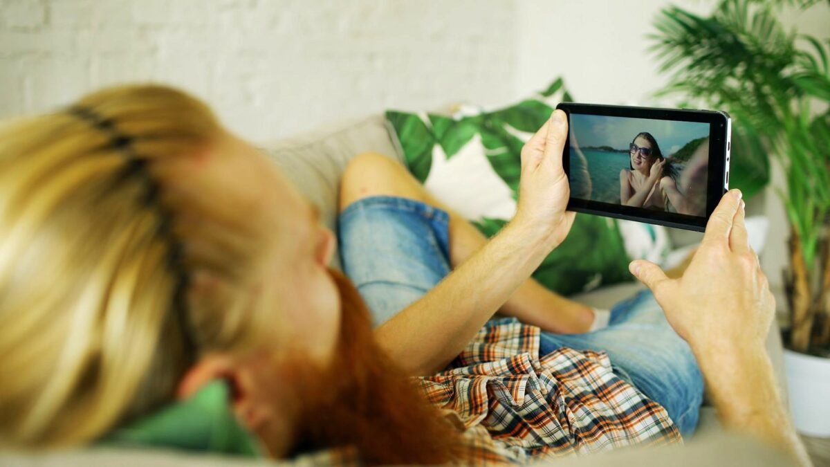 A man on a sofa watching a video on a tablet on his own