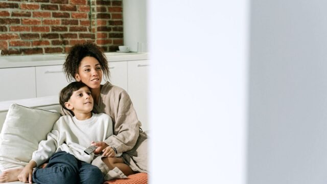 Child sitting on a sofa and watching a television screen at home