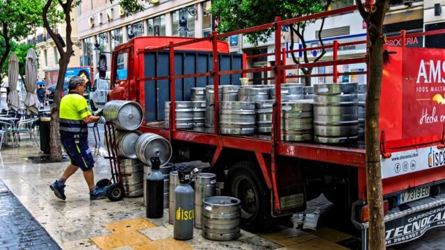 Man unloading beer kegs from a truck in Valencia, Spain.
