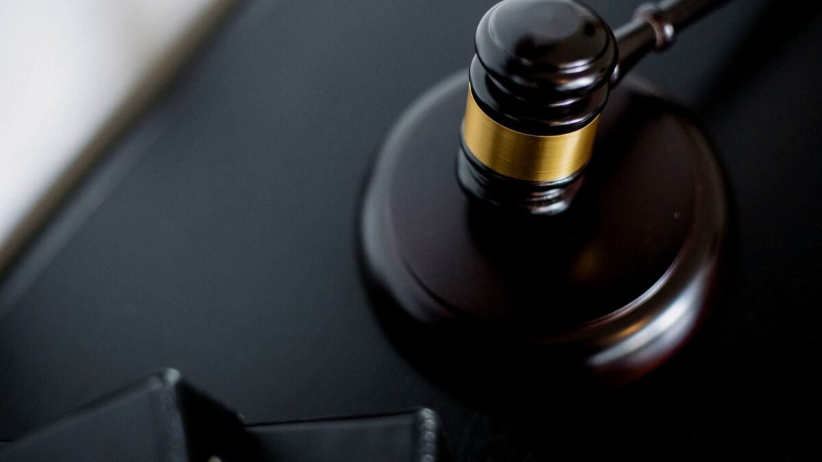 Wooden gavel on a round table next to folders in a courtroom