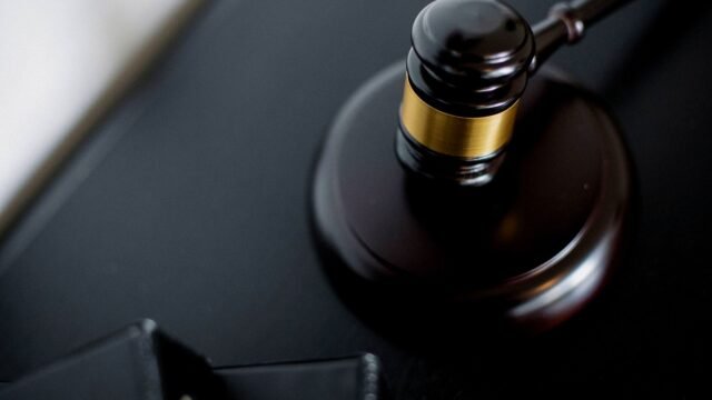 Wooden gavel on a round table next to folders in a courtroom