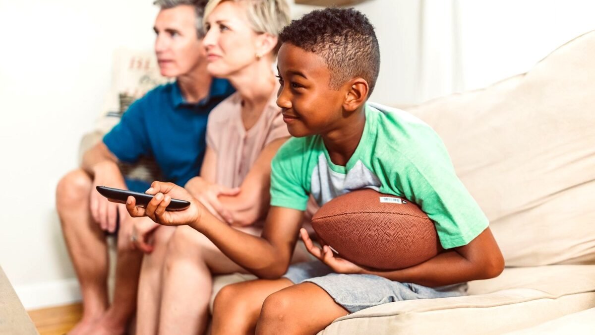 Family sitting on a sofa watching television together in a bright living room