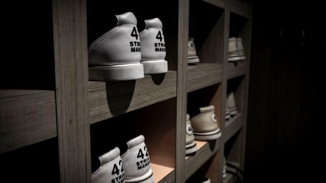 White trainers in size 42 lined up on a wooden shop shelf