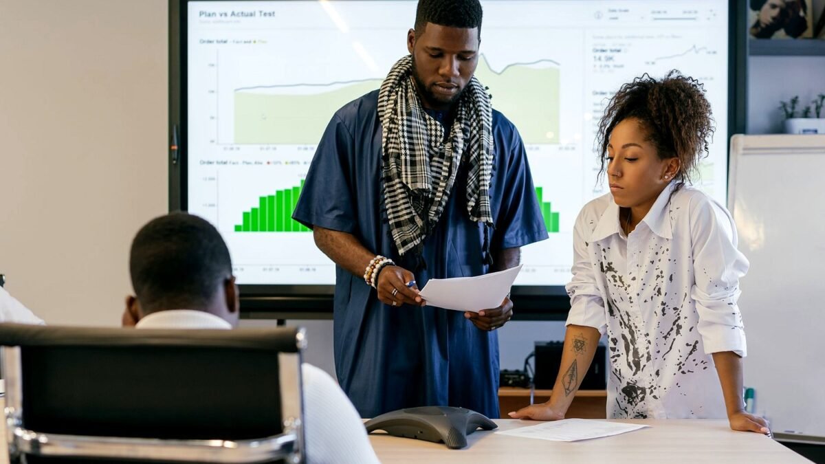 Two colleagues going through printed charts at a meeting table