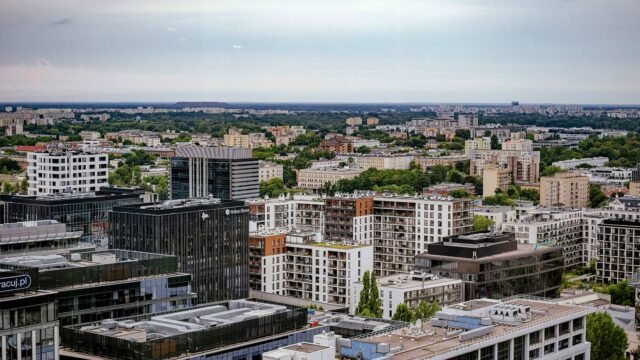 Aerial view of Warsaw showcasing modern and residential architecture against a lush backdrop.