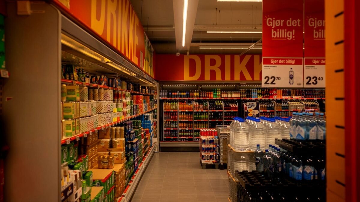 Shelves of soft drink bottles and cans in a supermarket aisle
