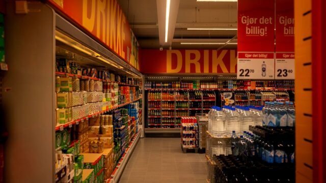 Shelves of soft drink bottles and cans in a supermarket aisle