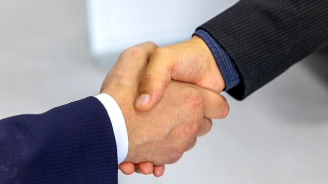 Two people shaking hands during a meeting in an office