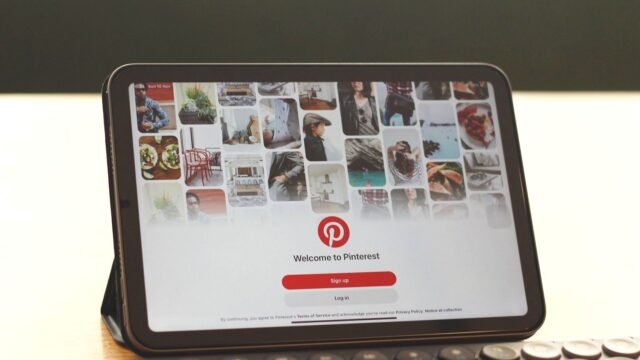 Tablet on a desk showing the Pinterest home feed next to a keyboard
